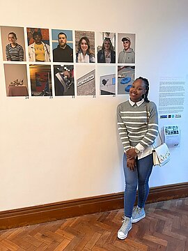 Vania stood next to her artwork at the exhibit of portraits