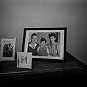 A black and white image of framed family photographs on a table