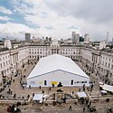 A white tent in Someset House grounds with people walking around, with a view of London in the background and Photo London signs up