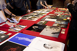 Photography prints on a table with hands looking through them
