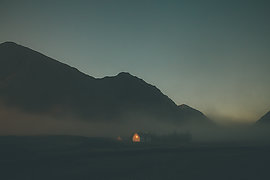 Twilight landscape with illuminated building in distance.